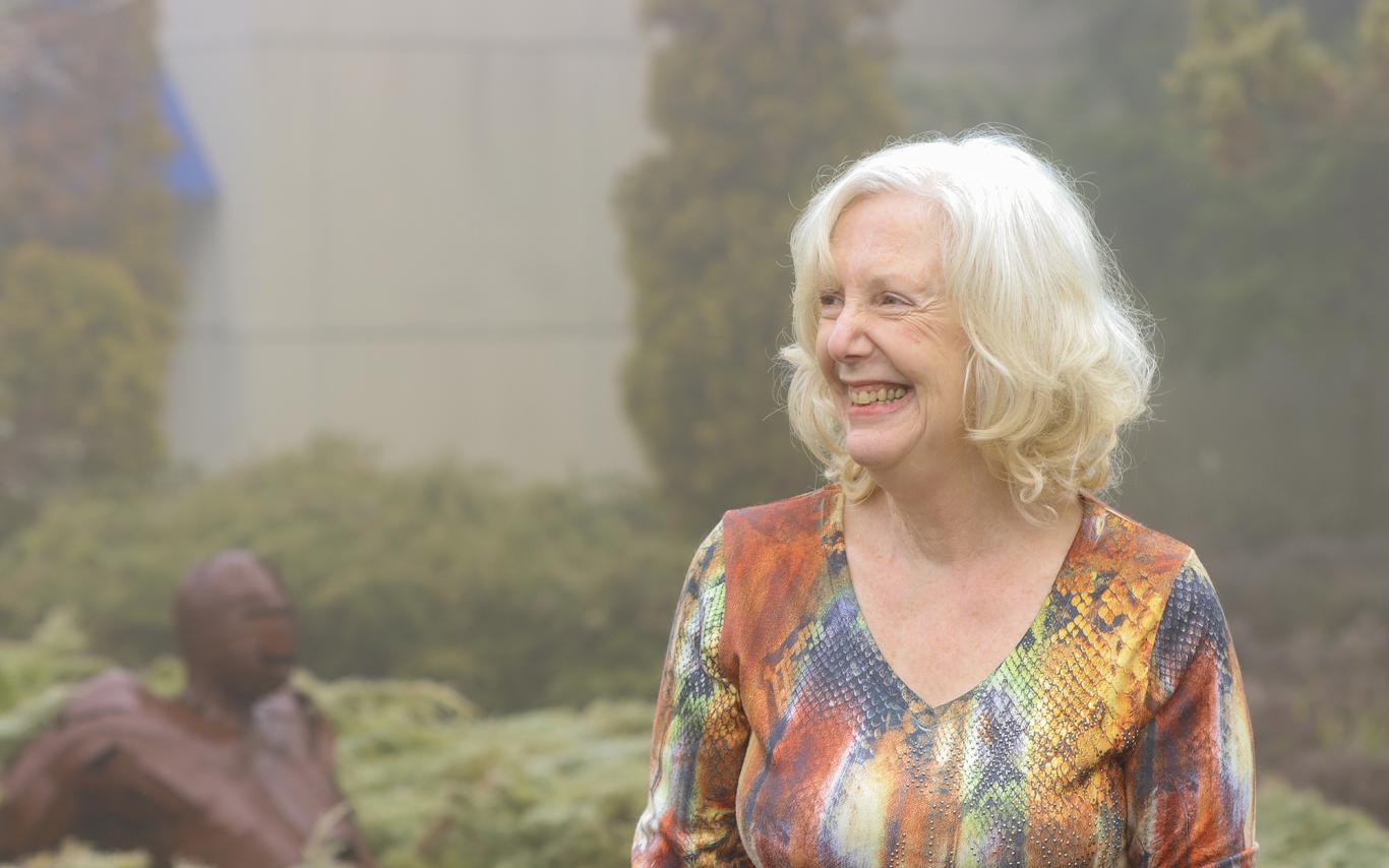 Pam Vickars stands in a garden area.