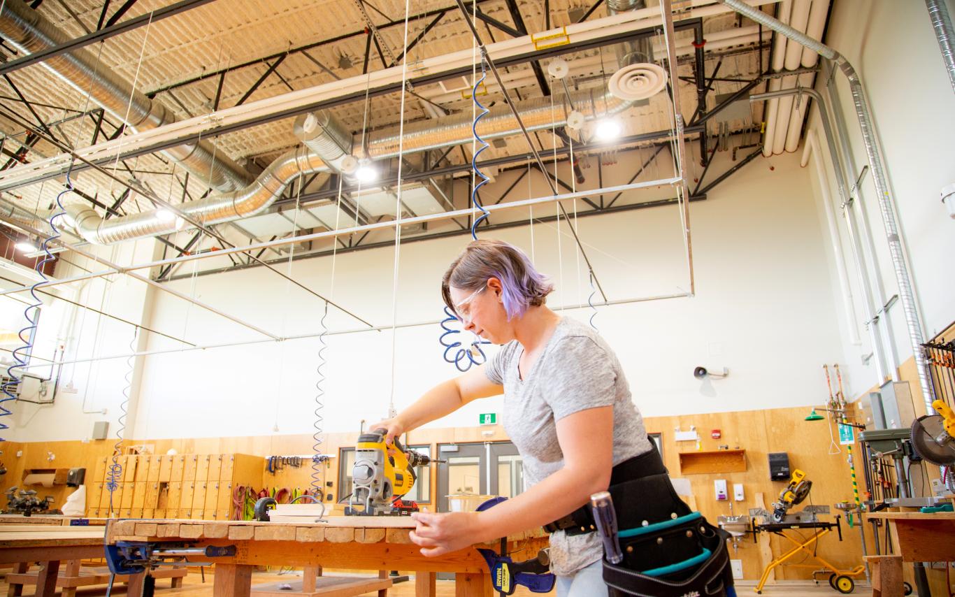 Female cutting a board in carpentry shop